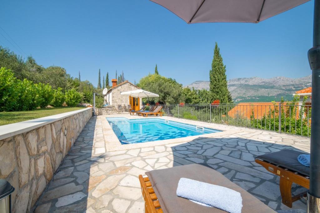 a swimming pool in a backyard with an umbrella at Villa Lucija in Gruda