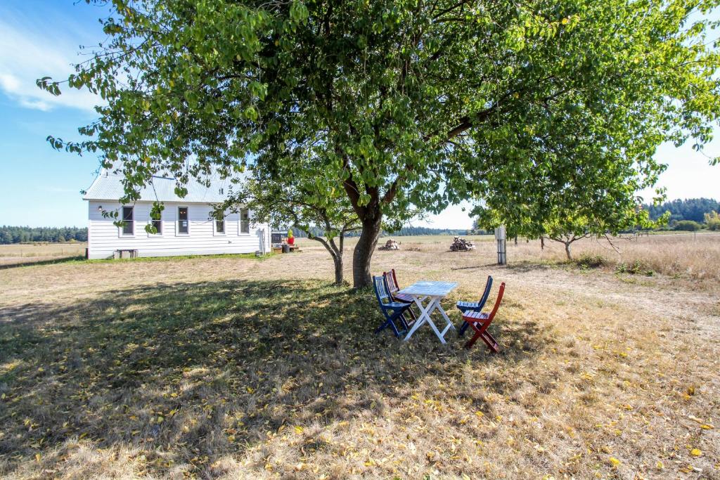 een tafel en stoelen onder een boom voor een huis bij Historic Officer's Farmhouse at OLF in Coupeville