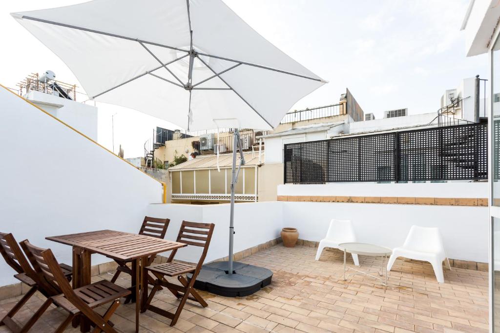 un patio con mesa, sillas y sombrilla en Apartamentos San Lorenzo, en Sevilla