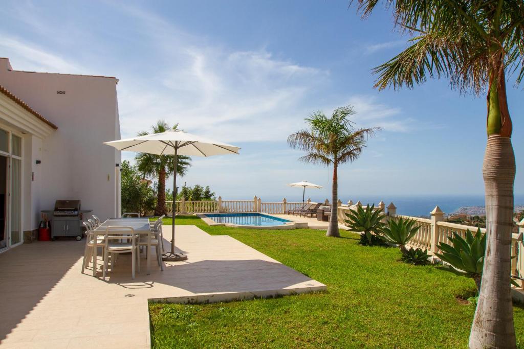 a patio with a table and an umbrella and the ocean at Casa Bonita in Algarrobo