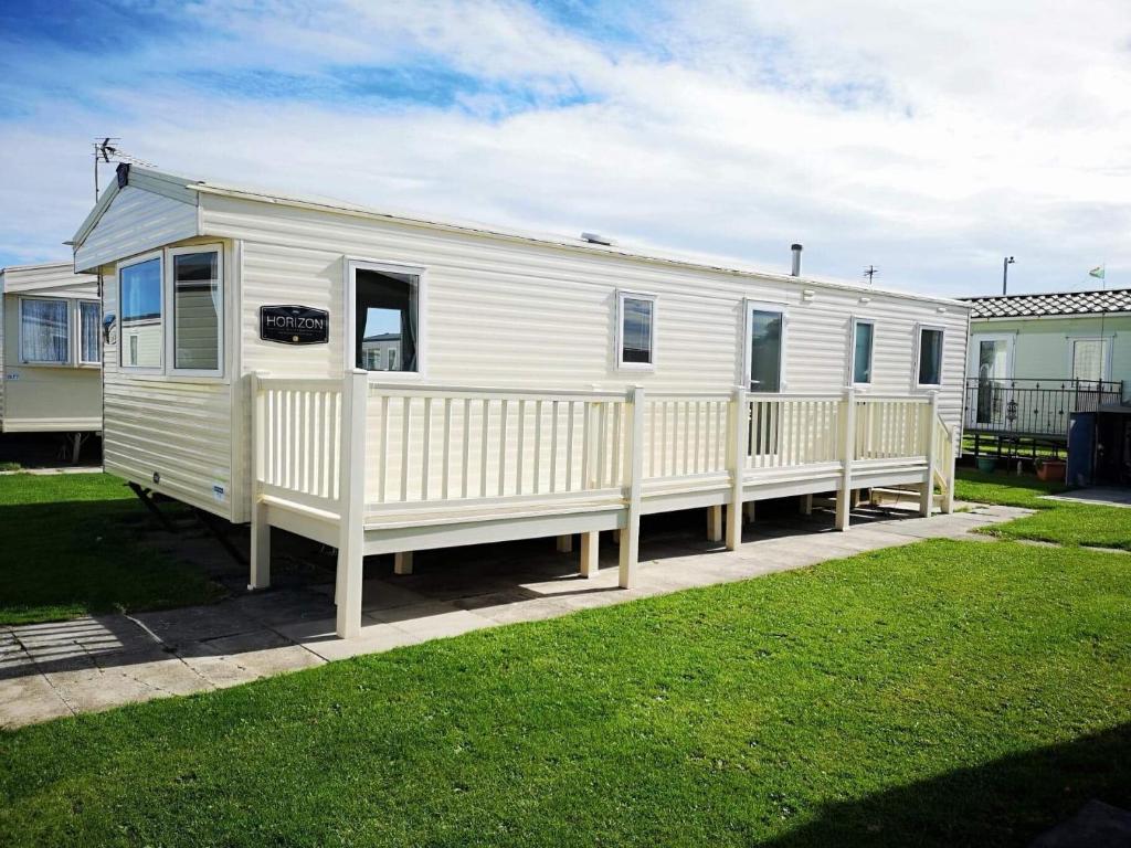 a white mobile home with a white fence at Caravan Retreats in Conwy