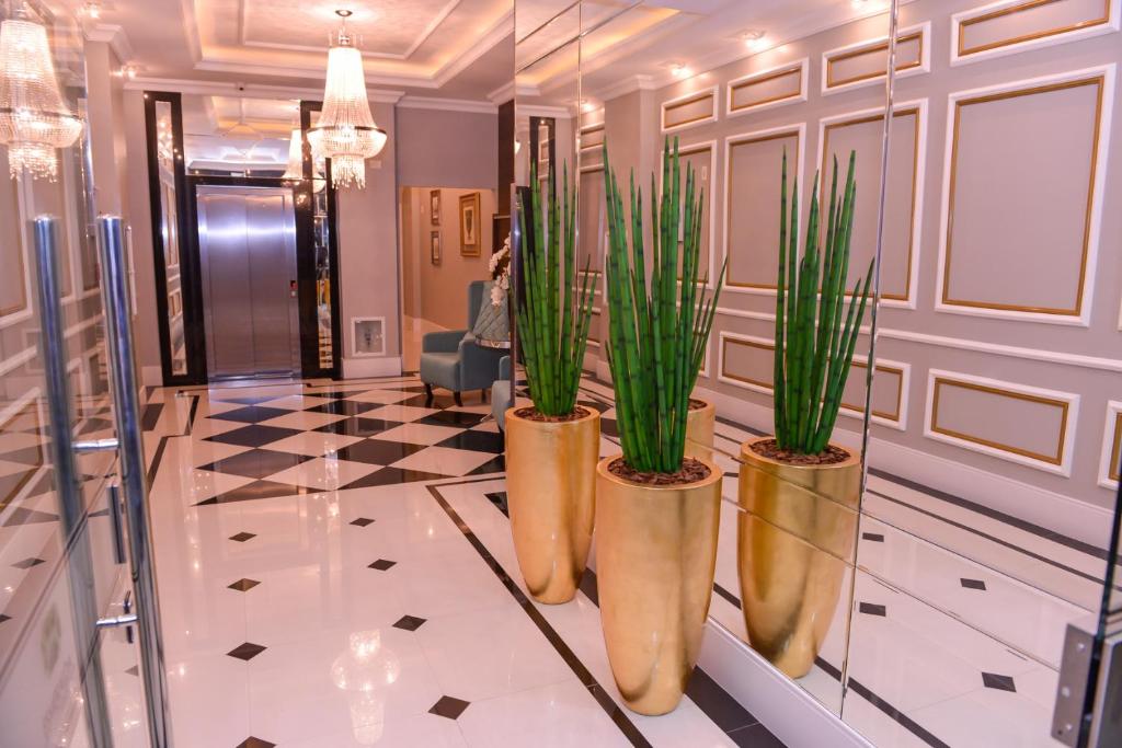 een lobby met drie potplanten in gouden vazen bij Meia Praia Apartamento Perfeito in Meia Praia