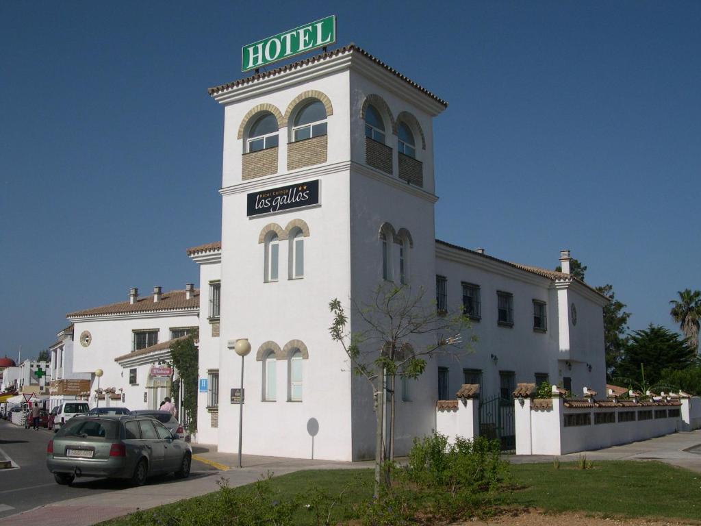 un bâtiment avec une tour d'horloge munie d'un panneau. dans l'établissement Hotel Cortijo Los Gallos, à Chiclana de la Frontera