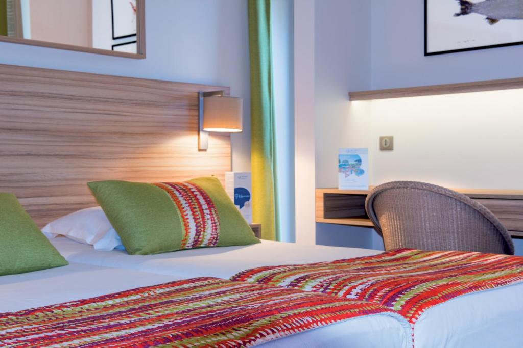 a hotel room with a bed with green pillows at Hôtel Vacances Bleues Delcloy in Saint-Jean-Cap-Ferrat