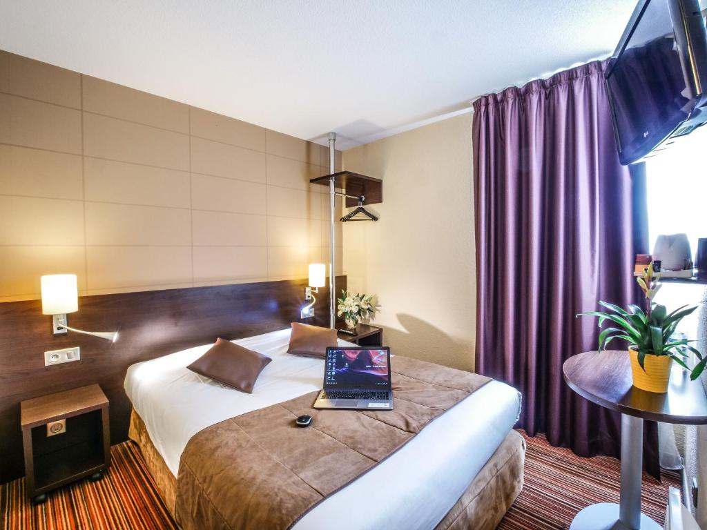 a hotel room with a bed with a laptop on it at Hôtel Inn Design Resto Novo Alençon in Alençon