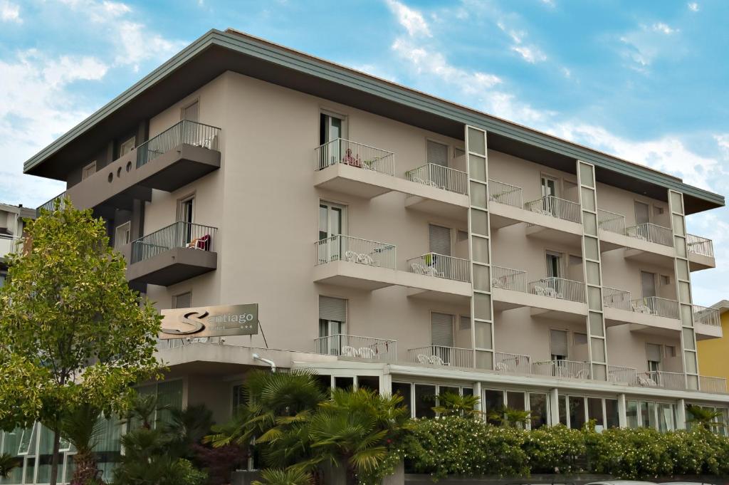 an apartment building with balconies and trees at Hotel Santiago in Lido di Jesolo