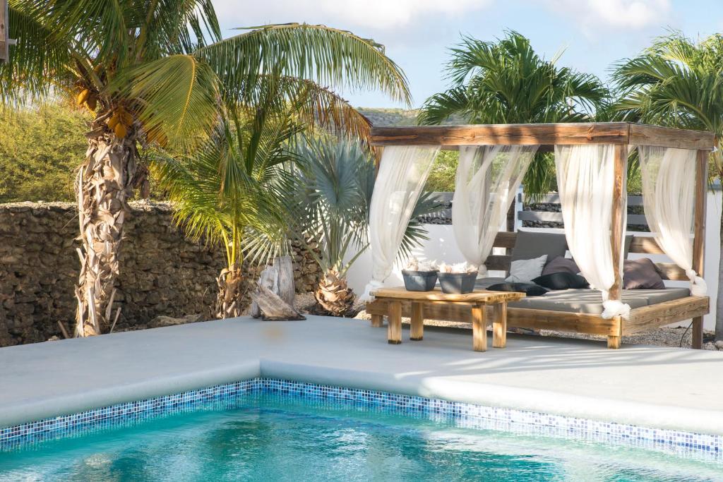 a pool with a gazebo and a table next to a pool at Hakuna Matata Bonaire - Beach & Diving in Kralendijk