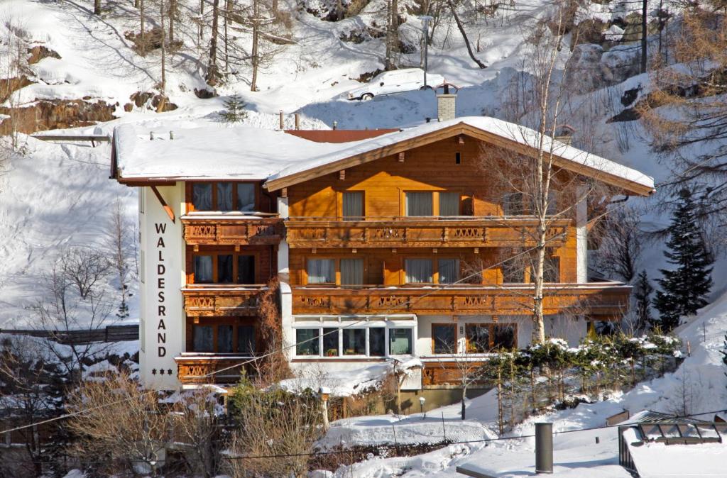 ein großes Holzhaus im Schnee in der Unterkunft Appartements Waldesrand in Sölden