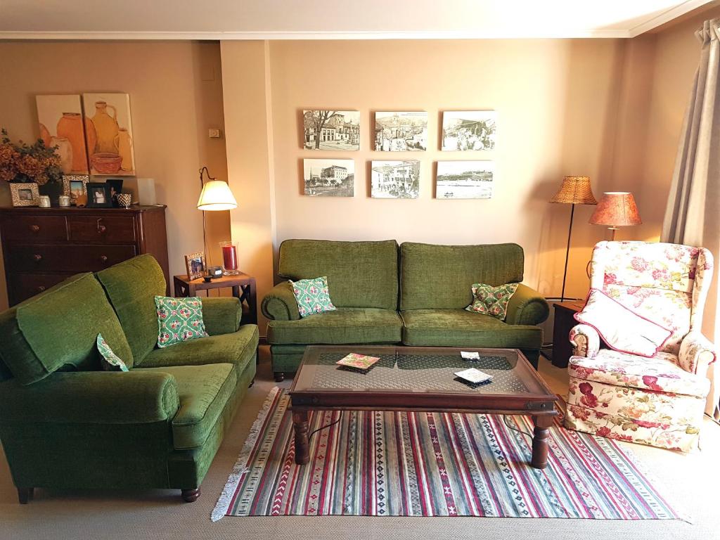 コミージャスにあるCasa familiar en el centro de Comillasのリビングルーム(緑のソファ2台、コーヒーテーブル付)