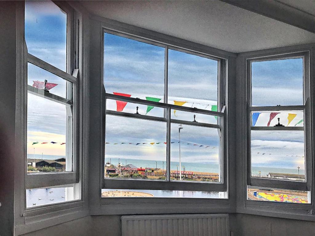een kamer met 3 ramen met uitzicht op het strand bij Smugglers Cottage in Hastings