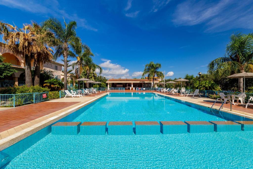 a large swimming pool with chairs and palm trees at Mare Azzurro in Cardedu