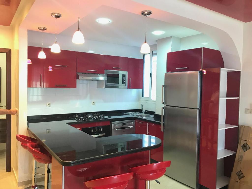 a kitchen with red cabinets and a stainless steel refrigerator at Le nid du centre ville in Rabat