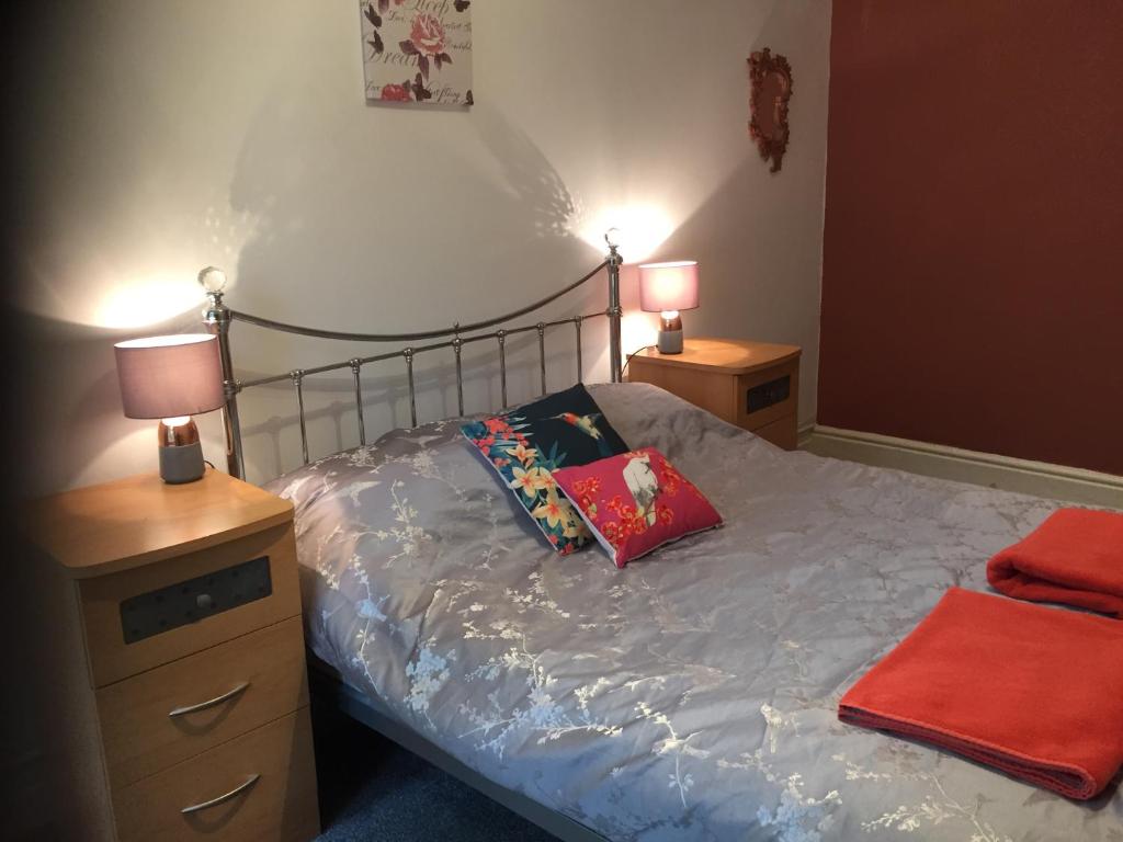 een slaapkamer met een bed met 2 nachtkastjes en 2 lampen bij Apartment close to Pavilion gardens in Buxton