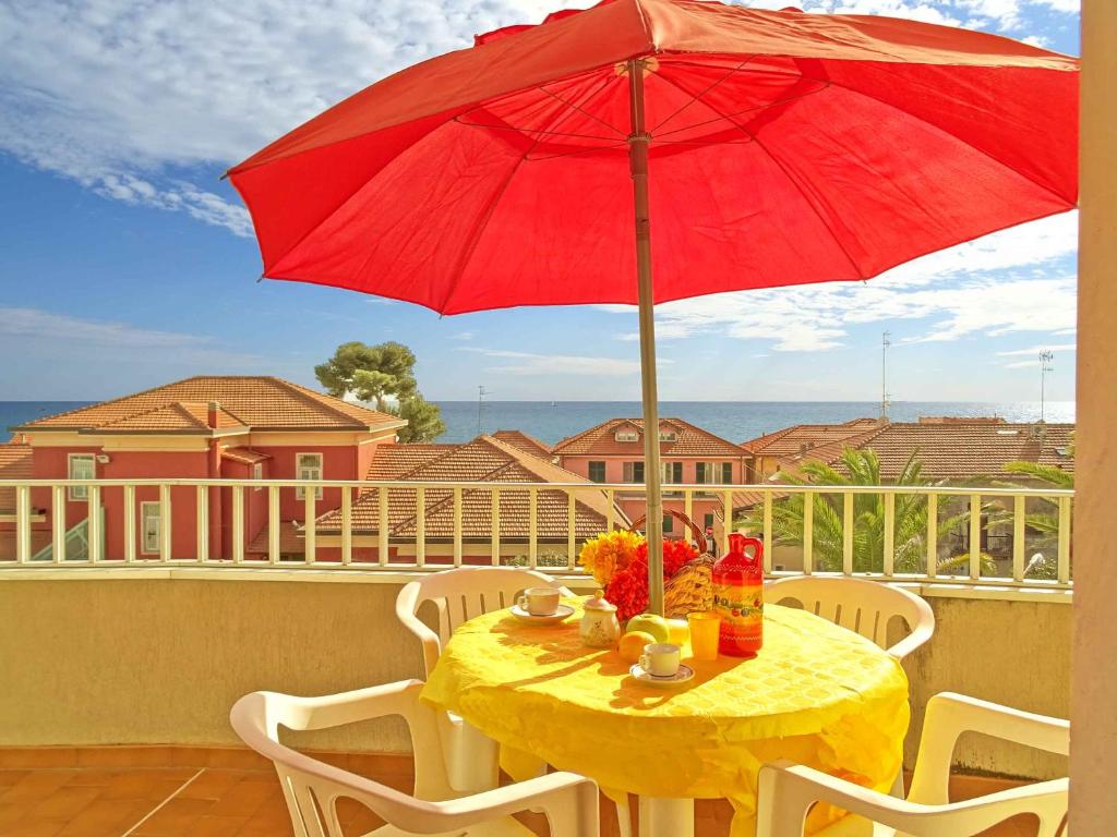 a table with a red umbrella on a balcony at Casa Vacanze Stelle Marine in Santo Stefano al Mare