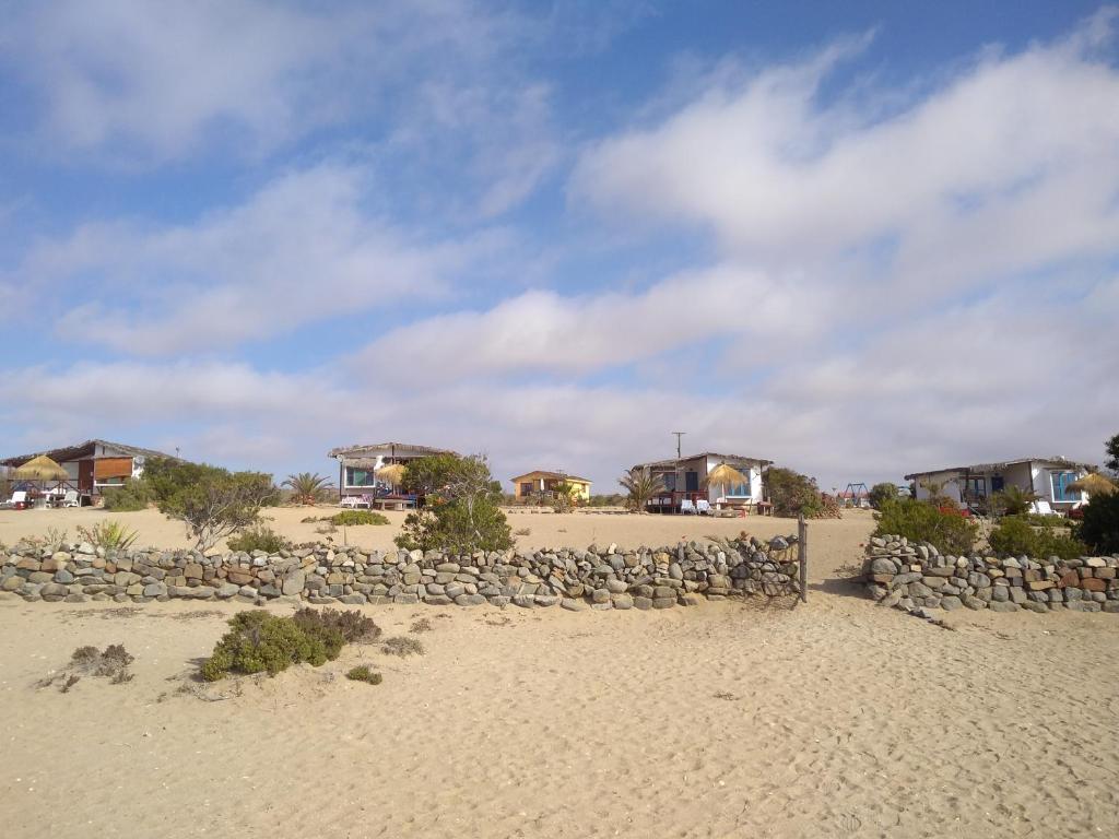 una playa con una valla de piedra y algunas casas en Cabañas Paraiso, en Bahía Inglesa