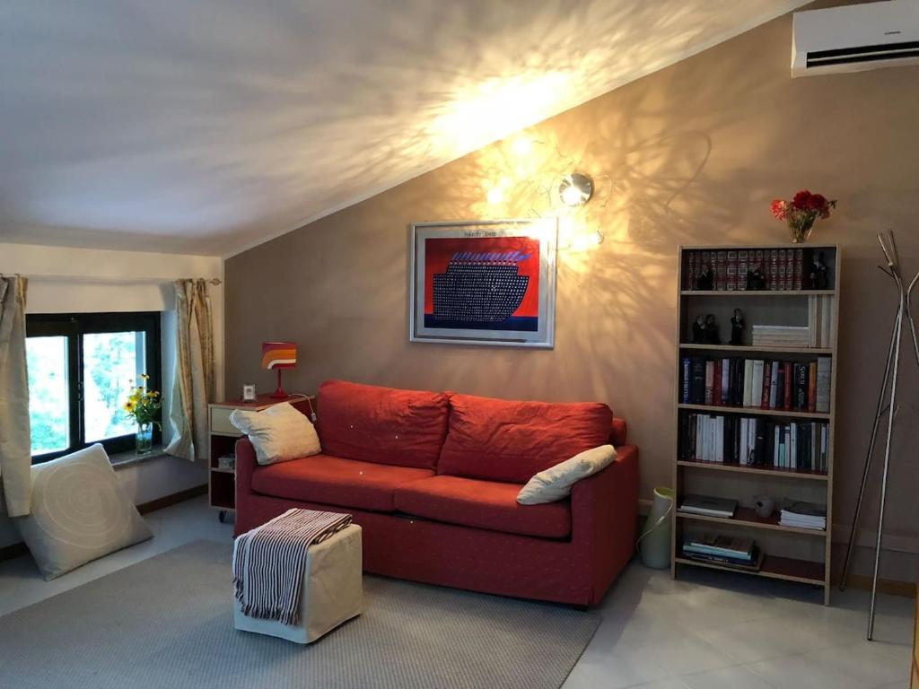 a living room with a red couch and a book shelf at La mansarda di Orni in Ivrea