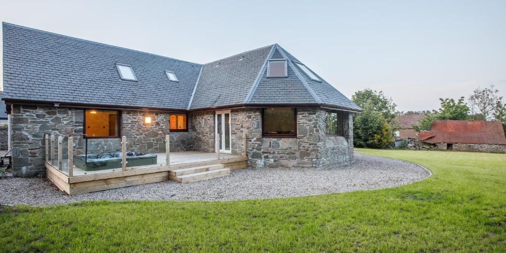 a stone cottage with a deck and a house at North Balkello Cottage in Dundee