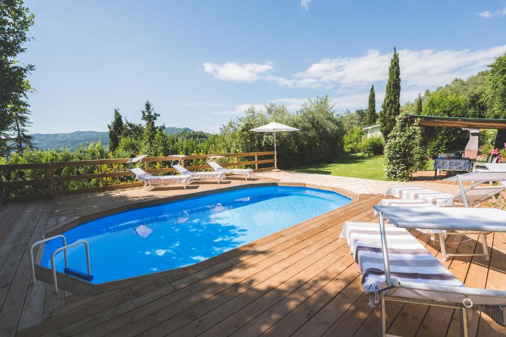 a swimming pool on a wooden deck with chairs around it at Exclusive beautiful pool house surrounded by greenery, modern, luxury finishes in Camaiore