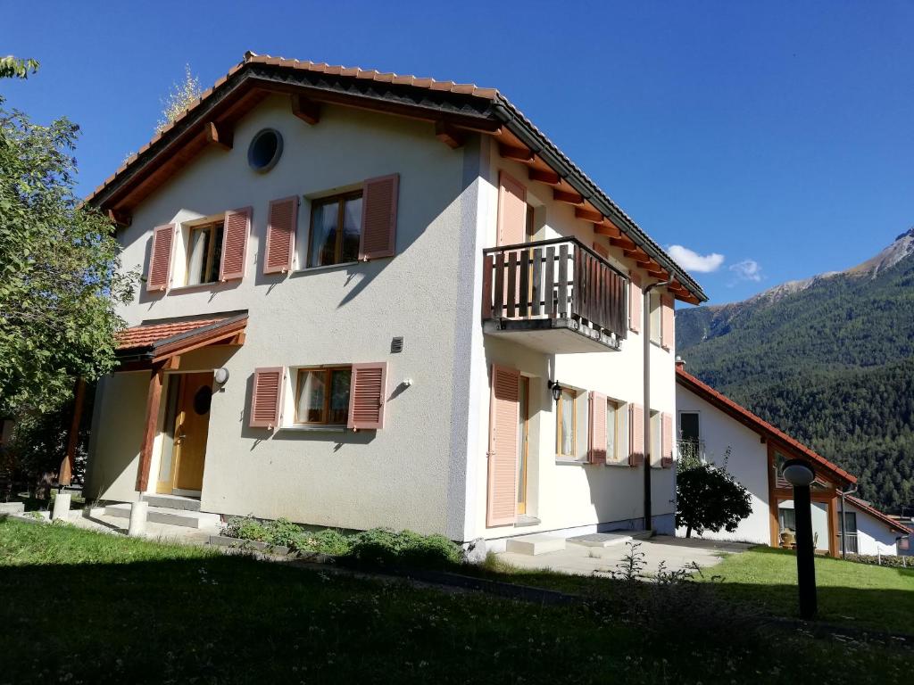 a white house with red shutters and a balcony at Chasa Ludwig Oben Hause in Scuol