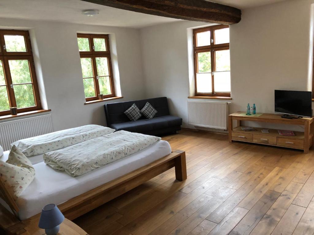 a bedroom with a bed and a couch and windows at Landhaus Hui Wäller in Beilstein