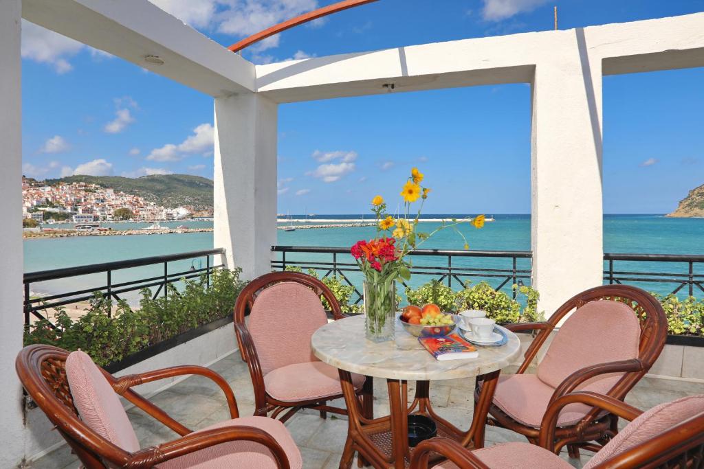 een tafel met stoelen en een vaas met bloemen op een balkon bij Mamma Mia in Skopelos Town