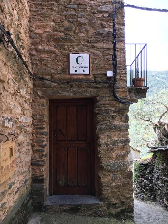 a stone building with a wooden door with a sign on it at Caserío de Ovejuela in Ovejuela