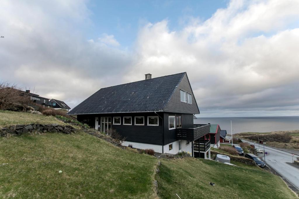 a house on top of a hill with the ocean at FaroeGuide in Tórshavn