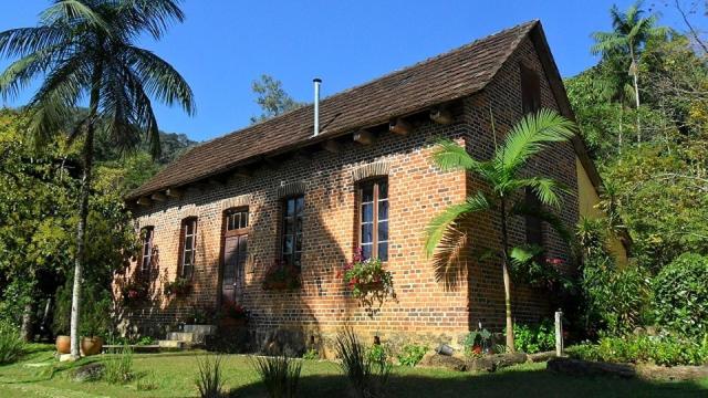 a brick house with a palm tree in front of it at Hospedagem Rural Fazenda Sacramento in Rodeio Doze