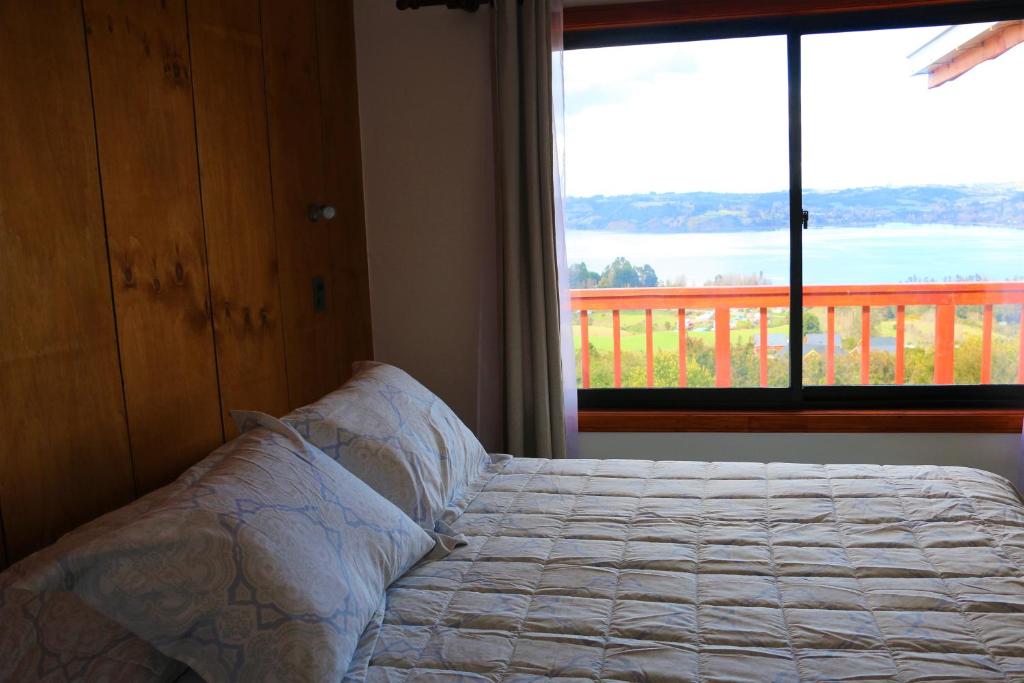 ein Schlafzimmer mit einem Bett und einem großen Fenster in der Unterkunft Terrazas de Nercon in Castro