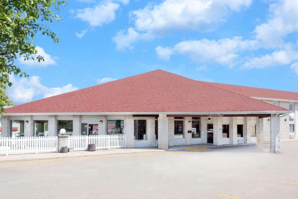 a building with a red roof and a white fence at Days Inn by Wyndham Jackson in Jackson