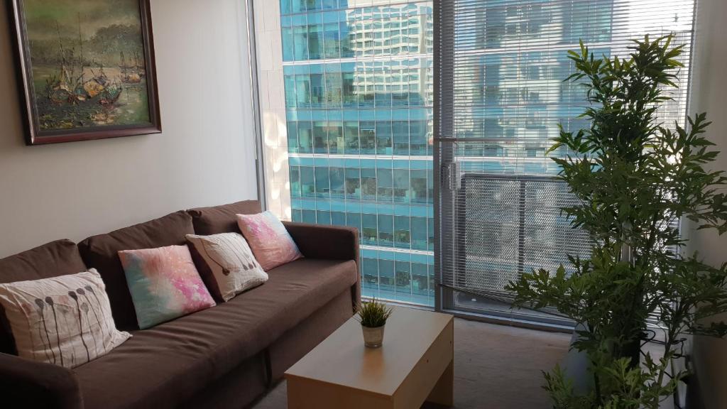 a living room with a couch and a large window at 2 bedrooms CBD FREE Tram apartment (Melb Central, China Town, Queen Victoria Market, Melbourne University, RMIT, etc) in Melbourne