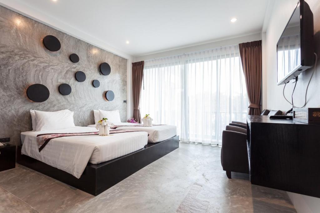 a bedroom with two beds and a large window at Aonang Viva Resort - SHA Plus in Ao Nang Beach