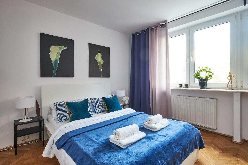 ein Schlafzimmer mit einem blauen und weißen Bett mit Handtüchern darauf in der Unterkunft Noctis Apartment Plac Grzybowski in Warschau