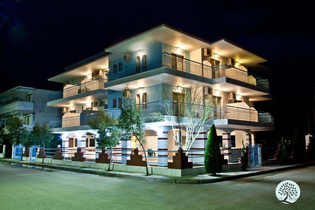 un gran edificio blanco con luces encendidas por la noche en Hotel Melissanthi en Paralia Dionysiou