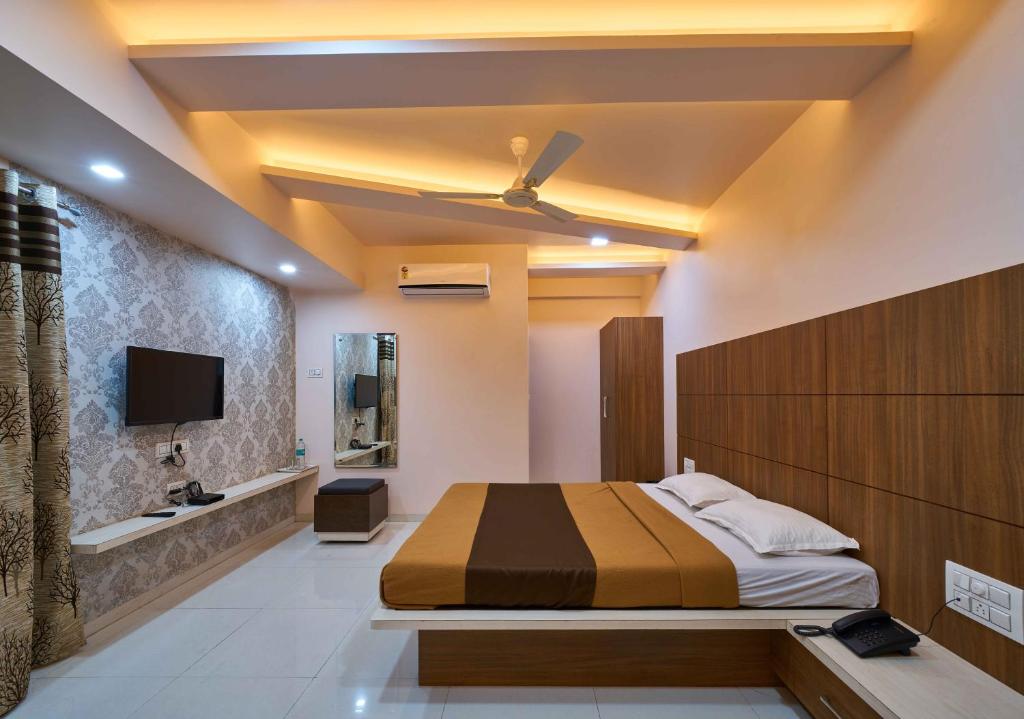 a bedroom with a bed and a tv on the wall at Hotel Ramkrishna Inn in Kolhapur