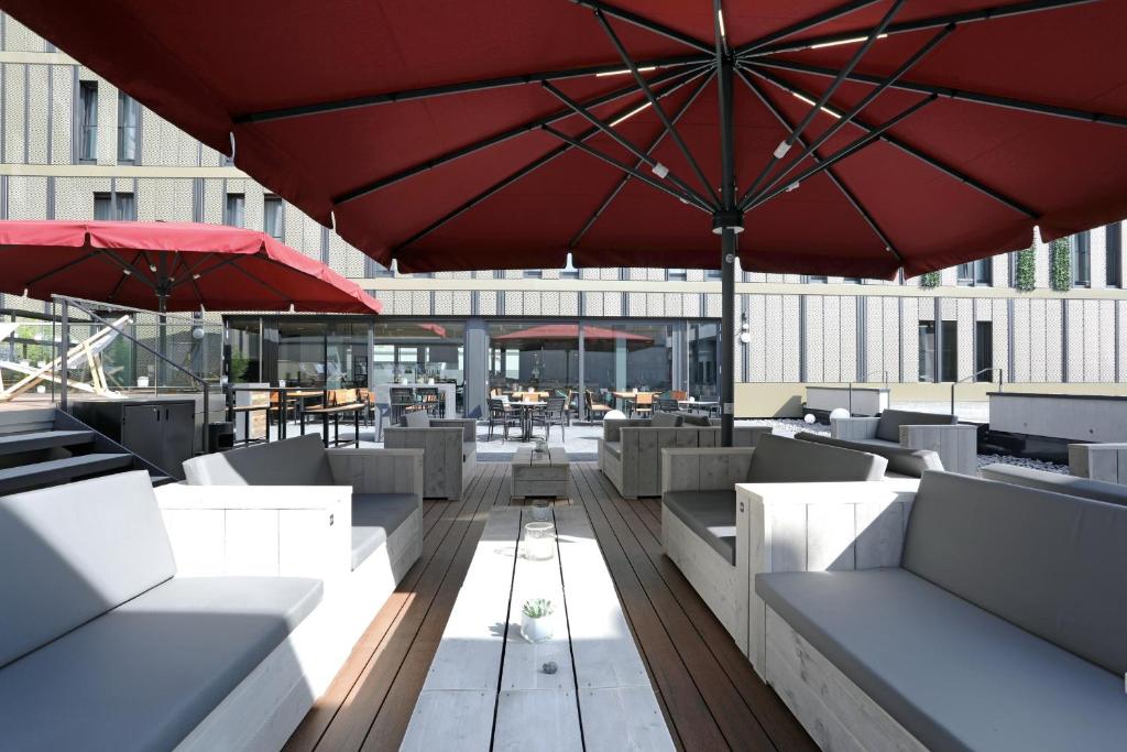 a patio with tables and chairs and an umbrella at sander Hotel in Koblenz