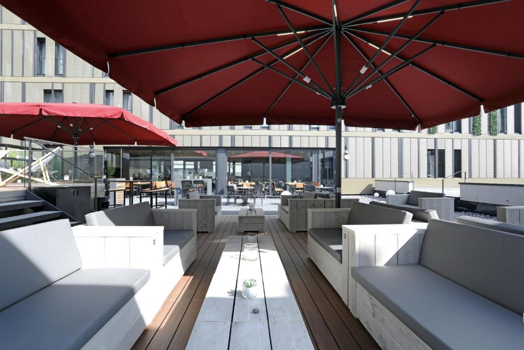 een patio met tafels en stoelen en een parasol bij sander Hotel in Koblenz