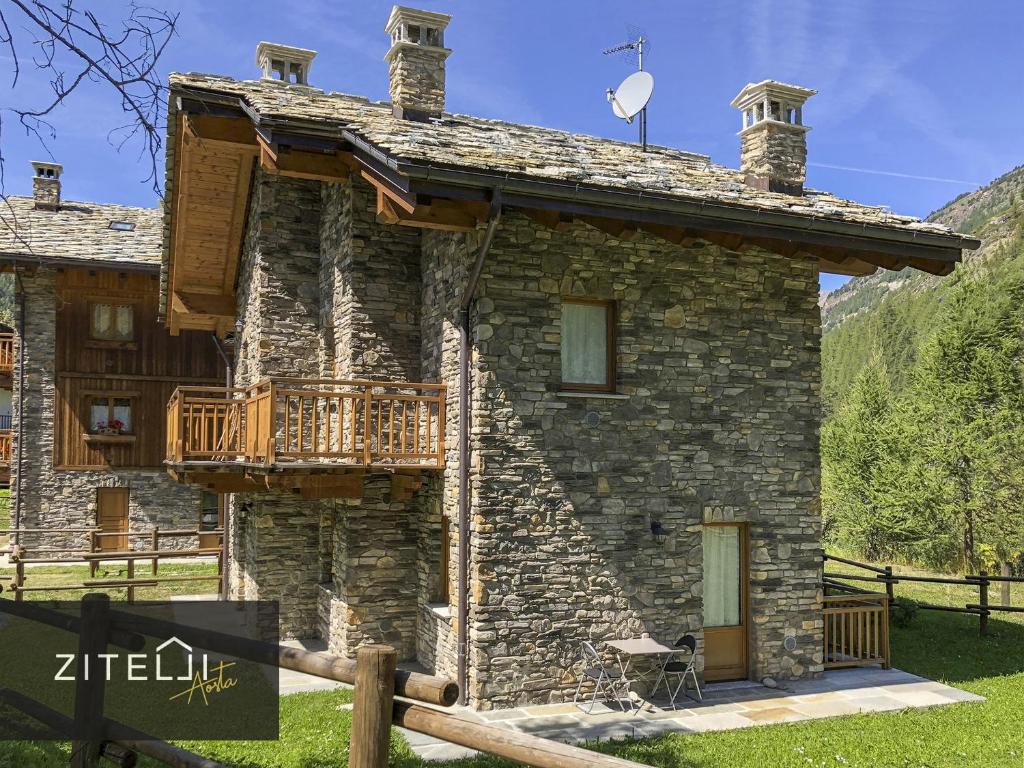 une maison en pierre avec un balcon sur le côté. dans l'établissement Zitelli Aosta, à Cogne