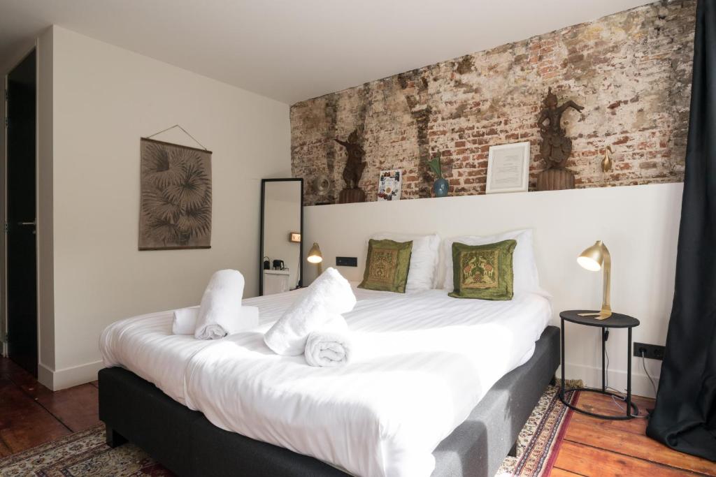 a bedroom with a large white bed with a brick wall at TWENTY FIVE Rooms in Amsterdam