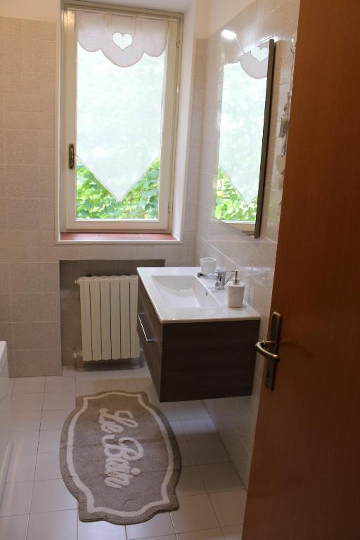 łazienka z umywalką, oknem i dywanem w obiekcie B&B Villa dei Cigni Reali w mieście Carpi