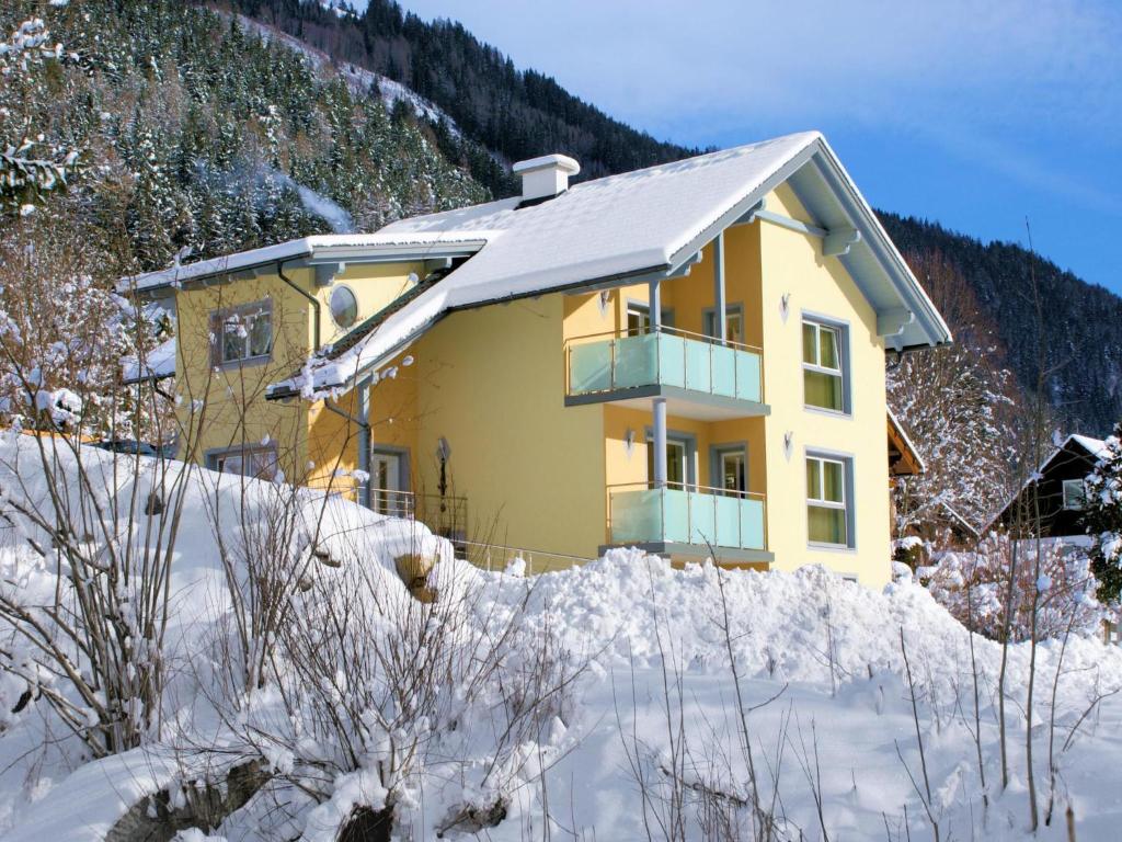 una casa amarilla con nieve delante en Appartementhaus Monika en Flattach
