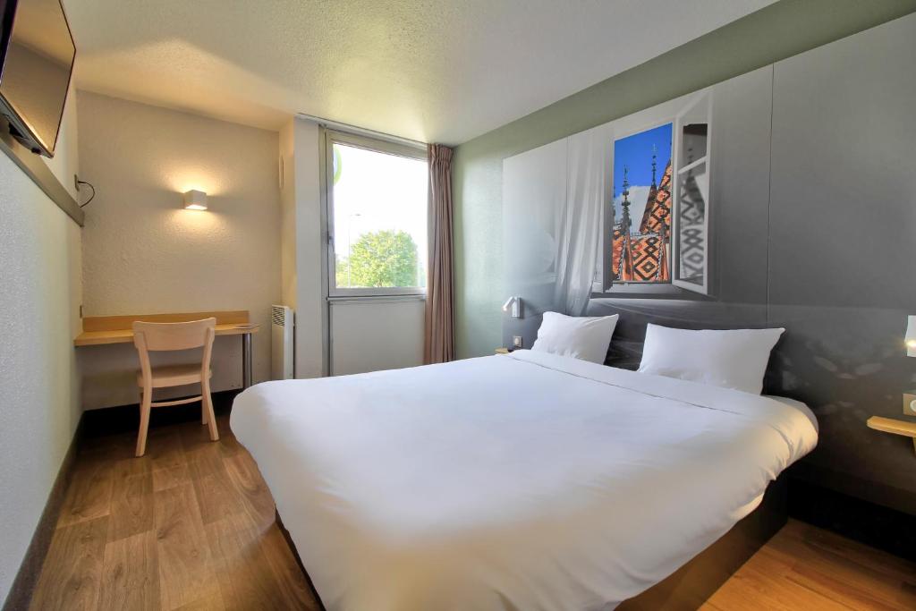Cette chambre comprend un grand lit blanc et une table. dans l'établissement B&B HOTEL Beaune Sud 1 Palais des Congrès, à Beaune