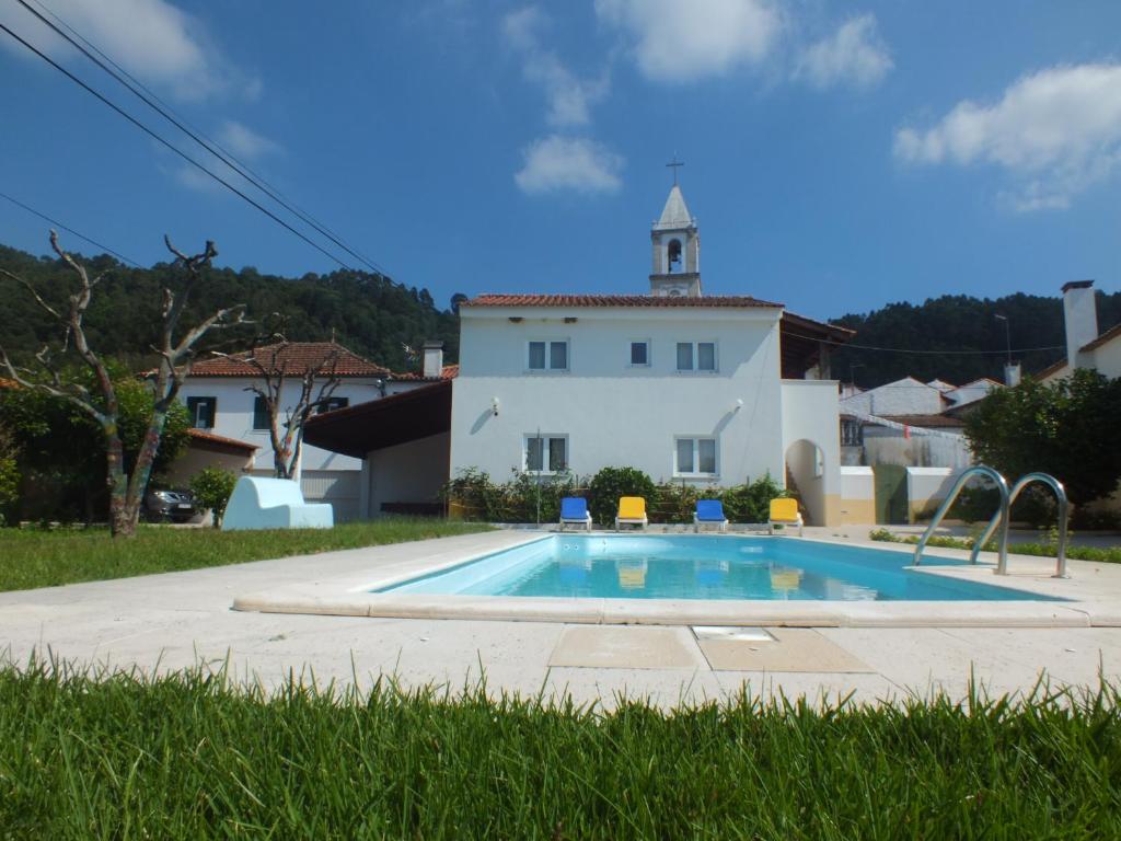 a swimming pool in front of a house with a church at Casa da Avó Tita in Cardeal