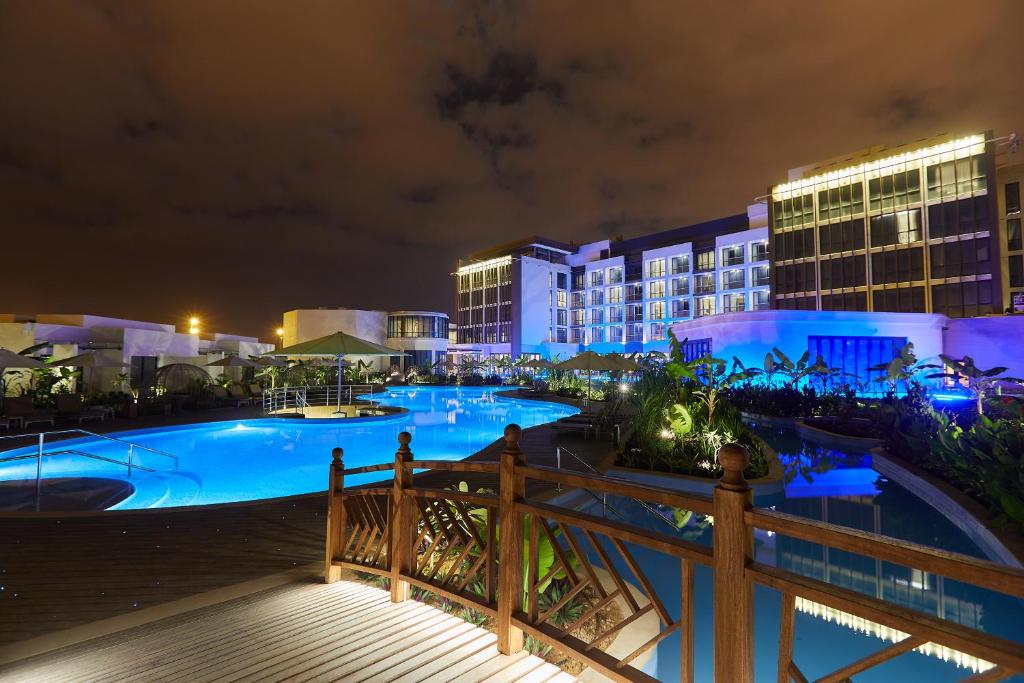 a resort with a large swimming pool at night at Millennium Resort Salalah in Salalah