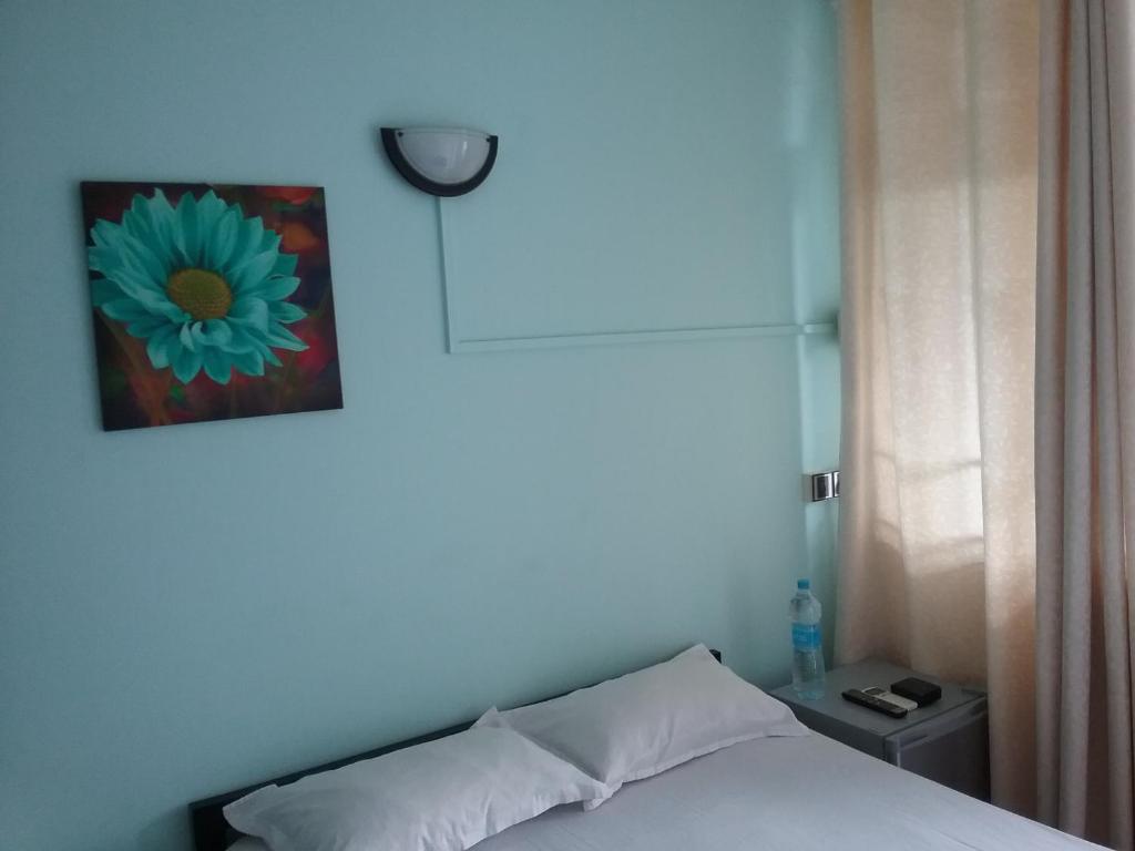 a bedroom with a bed with a flower picture on the wall at La Plaine Verte Guesthouse in Port Louis