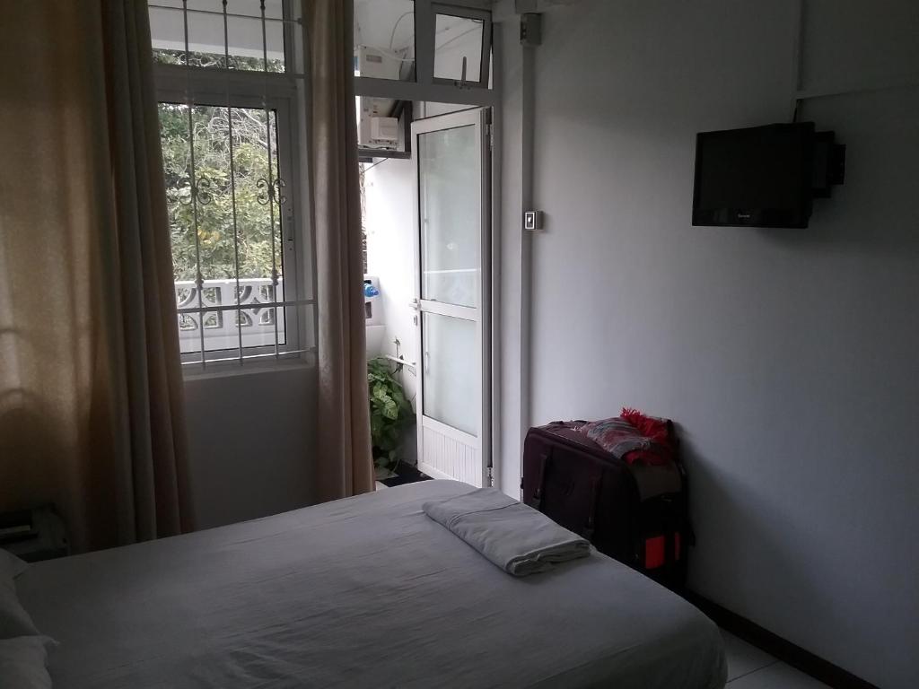 a bedroom with a bed and a window with a suitcase at La Plaine Verte Guesthouse in Port Louis