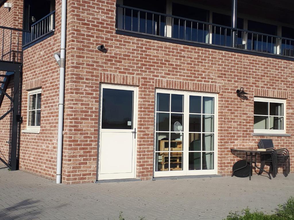 un edificio de ladrillo con una puerta blanca y una mesa en Klein Cambron, en Hulst