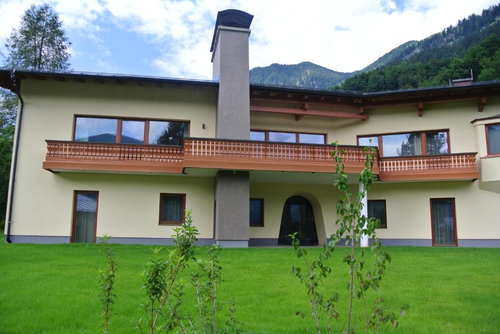 a house with a balcony on a green lawn at Villa Erika in Bad Hofgastein