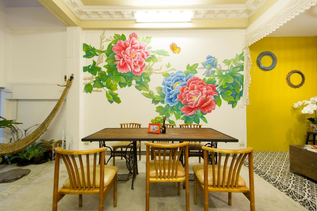 a dining room with a table and chairs with a flower mural at The Neighbors Hostel in Phuket Town