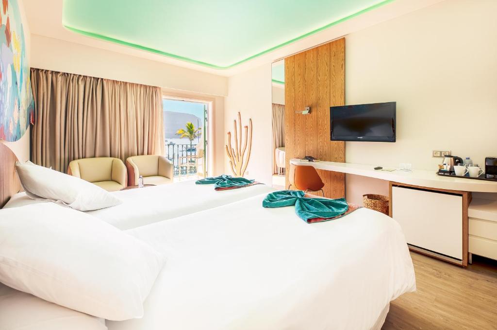 a hotel room with two beds and a television at Hotel LIVVO Puerto de Mogán in Puerto de Mogán